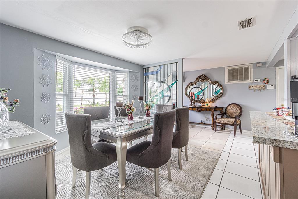 A dining room features a glass-topped table, gray upholstered chairs, and a large bay window — 3731 LATIMER STREET, NEW PORT RICHEY, FL