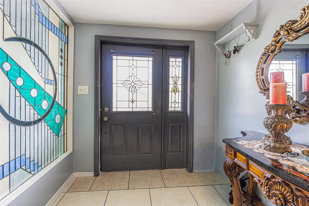 An entryway features a dark front door with glass panels, tile flooring, and a decorative mirror — 3731 LATIMER STREET, NEW PORT RICHEY, FL