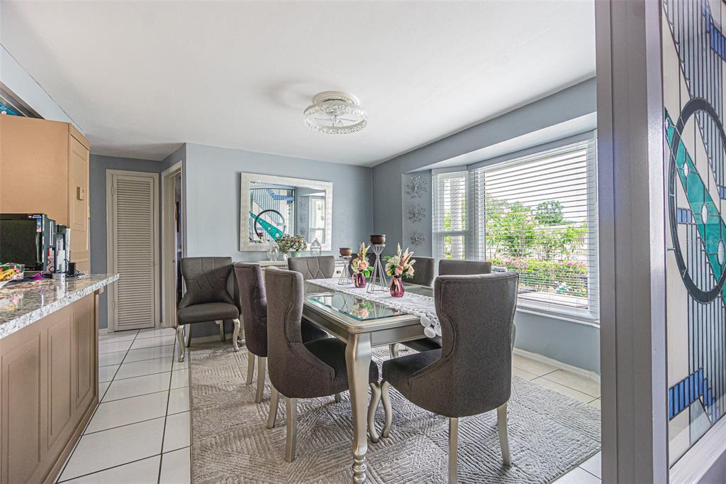 A dining room features a glass-topped table, gray upholstered chairs, and a large bay window — 3731 LATIMER STREET, NEW PORT RICHEY, FL