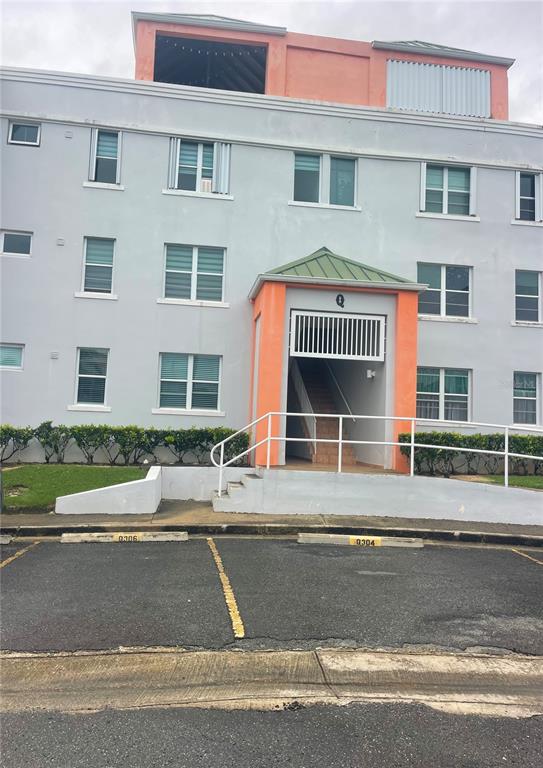 A multi-story apartment building exterior features a central orange entrance with stairs and parking spaces — Cond.180 Carretera 194 PR 180- CARR. ESTATAL NO. 194 ESTATES UNIT Q-206, FAJARDO, PR