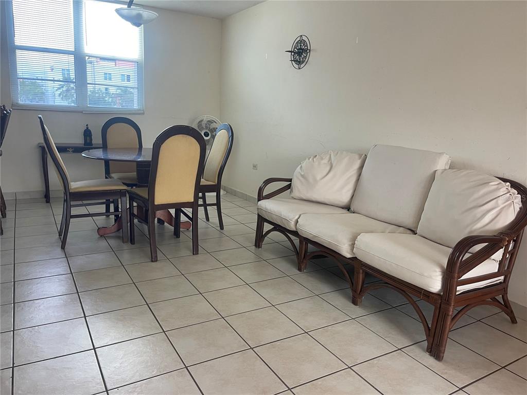 A dining area and living room with tile flooring, a rattan sofa, and a table set — Cond.180 Carretera 194 PR 180- CARR. ESTATAL NO. 194 ESTATES UNIT Q-206, FAJARDO, PR