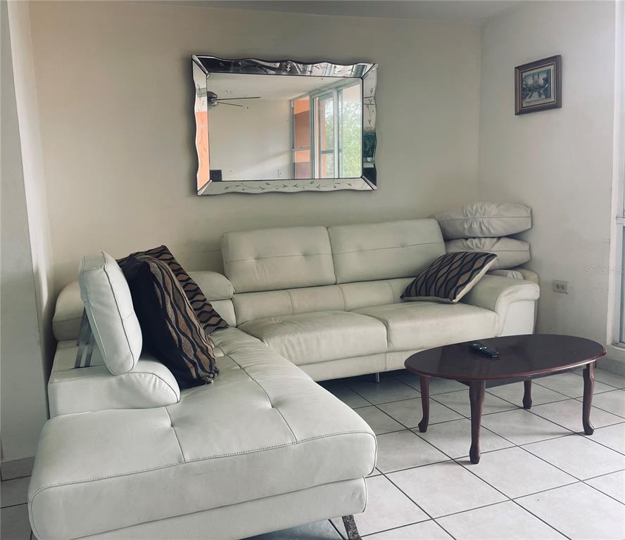 A white sectional sofa and a dark wood coffee table sit on a tiled floor — Cond.180 Carretera 194 PR 180- CARR. ESTATAL NO. 194 ESTATES UNIT Q-206, FAJARDO, PR