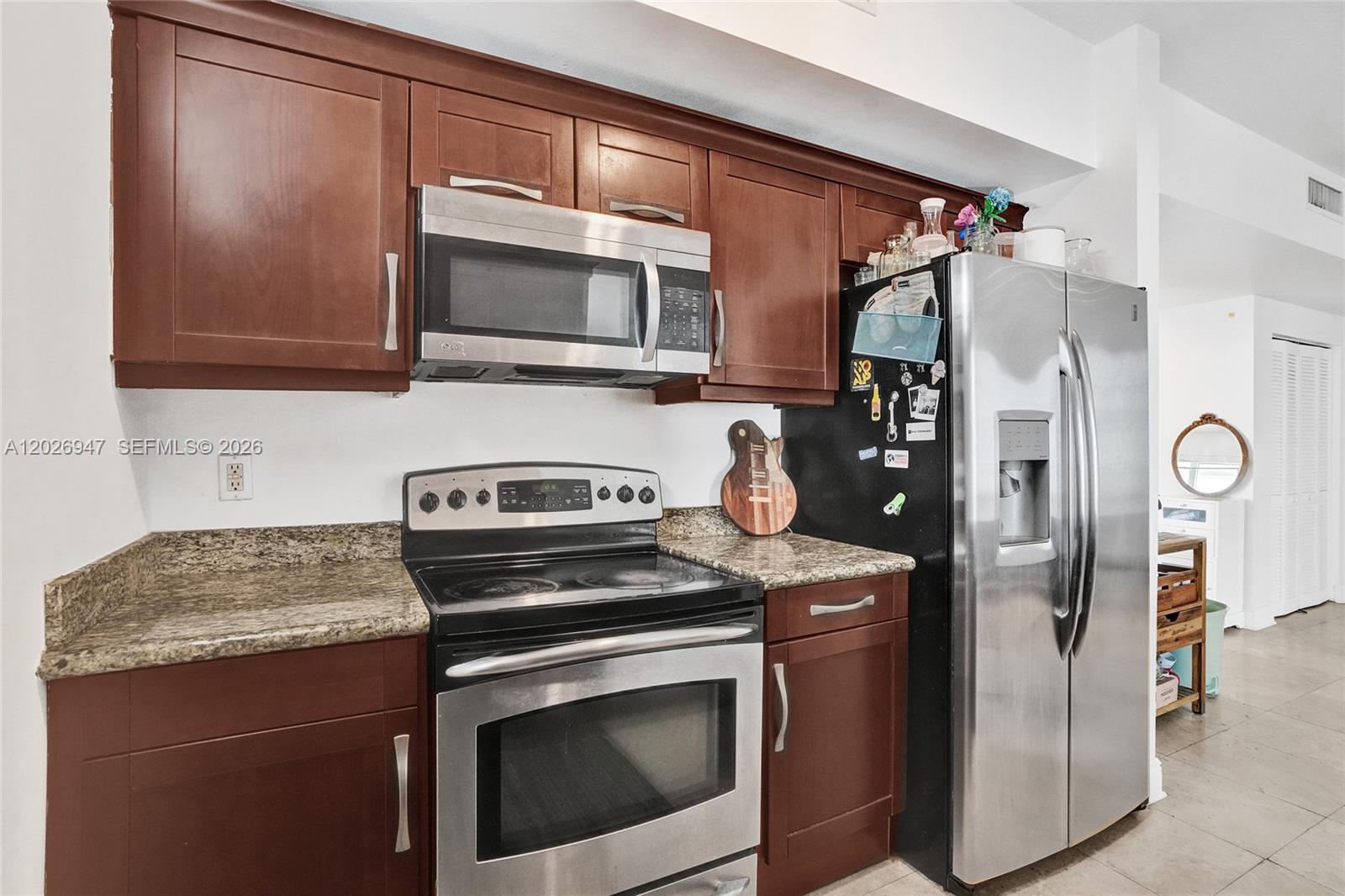 A kitchen features dark wood cabinets, granite countertops, and stainless steel appliances — 7275 SW 90th St # C410, Miami FL 33156, MIAMI, FL