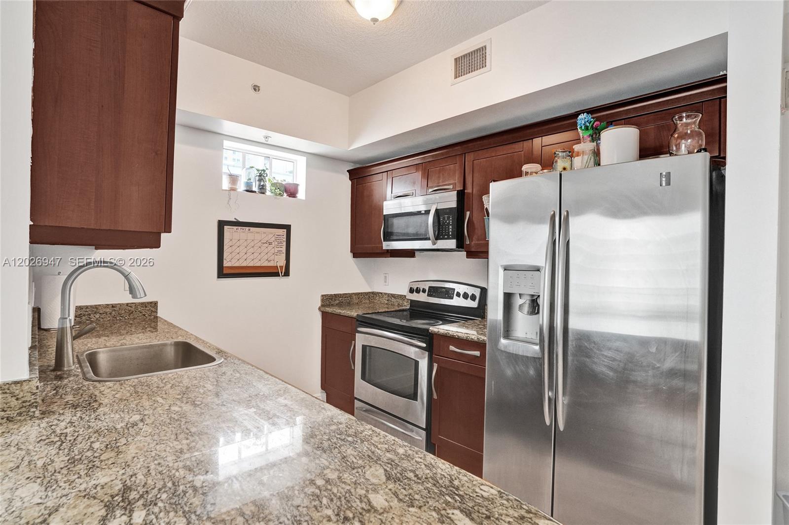 A kitchen features dark wood cabinets, granite countertops, stainless steel appliances, and a small window — 7275 SW 90th St # C410, Miami FL 33156, MIAMI, FL