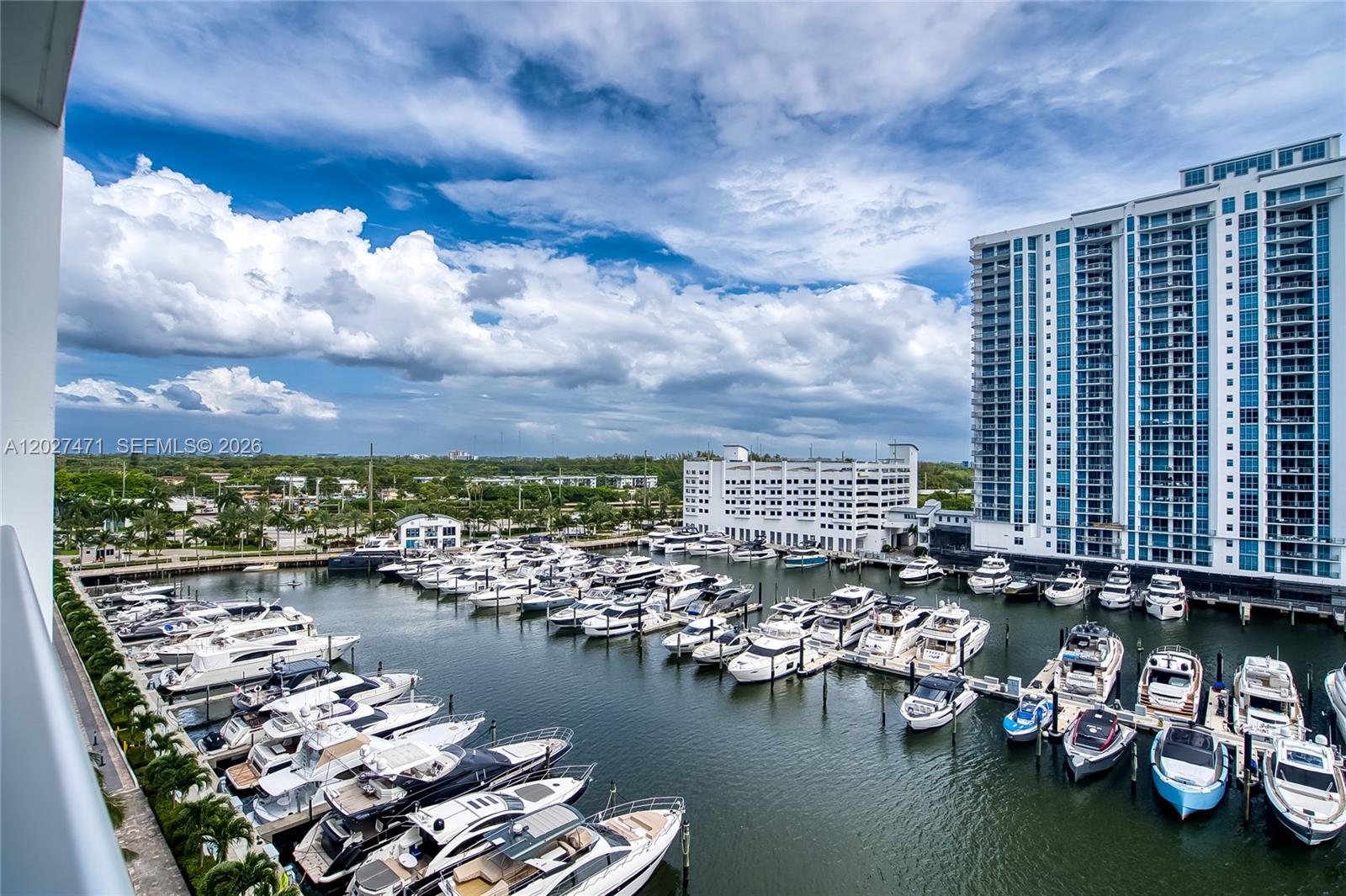 An elevated view shows a marina filled with numerous yachts beside a large apartment building — NORTH MIAMI BEACH, FL