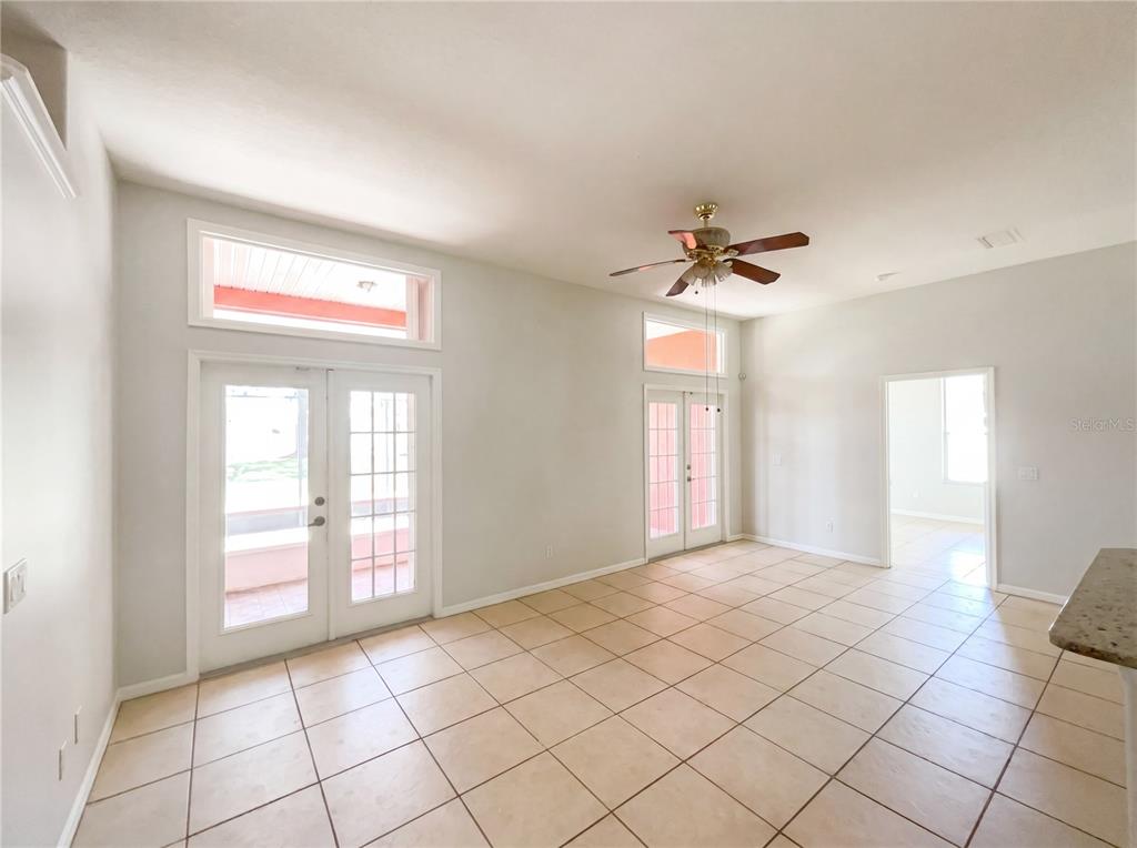 A bright room with light tile floors, a ceiling fan, and two sets of glass doors — 62 CORDONA DRIVE, KISSIMMEE, FL