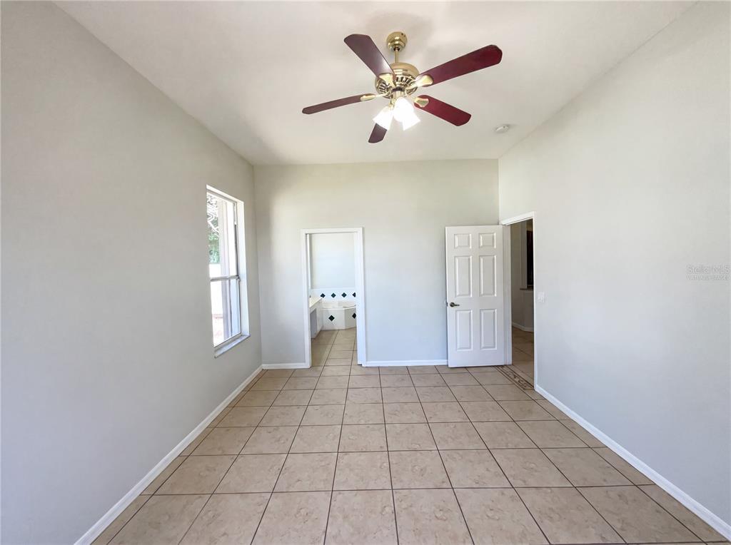 A room with light-colored walls, tiled flooring, a ceiling fan, and two doorways — 62 CORDONA DRIVE, KISSIMMEE, FL