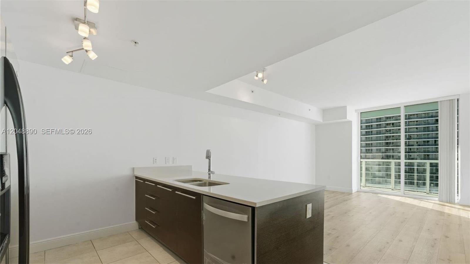 A modern kitchen island with a stainless steel dishwasher sits in an open-concept living space — MIAMI, FL