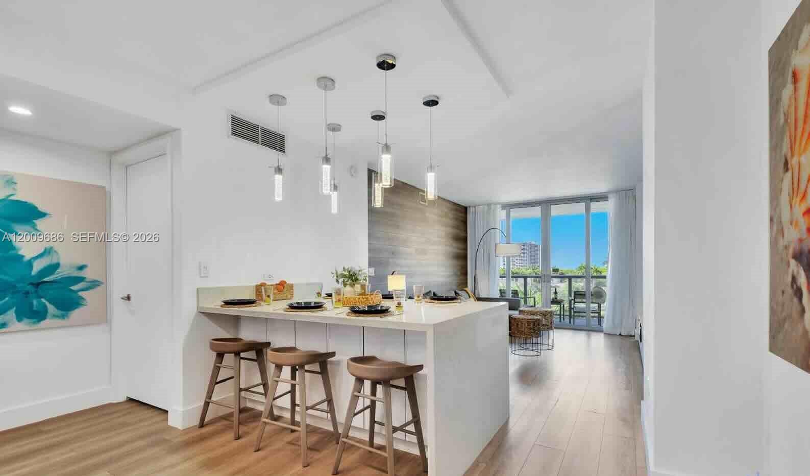 A modern kitchen island with bar stools sits in an open-concept living space — 2602 E Hallandale Beach Blvd # R506, Hallandale Beach FL 33009, HALLANDALE BEACH, FL