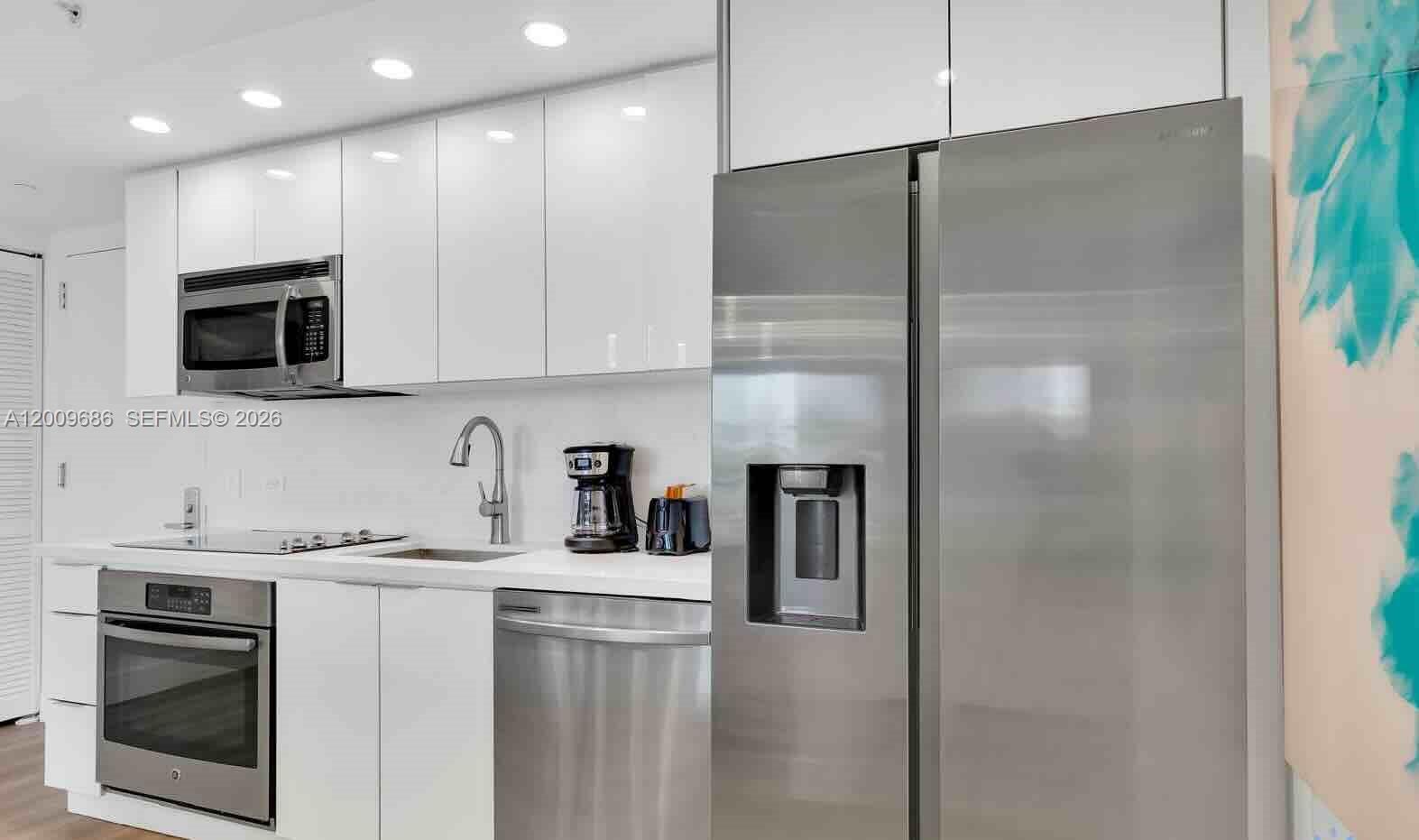 A modern kitchen features white cabinetry, stainless steel appliances, and a white countertop — 2602 E Hallandale Beach Blvd # R506, Hallandale Beach FL 33009, HALLANDALE BEACH, FL