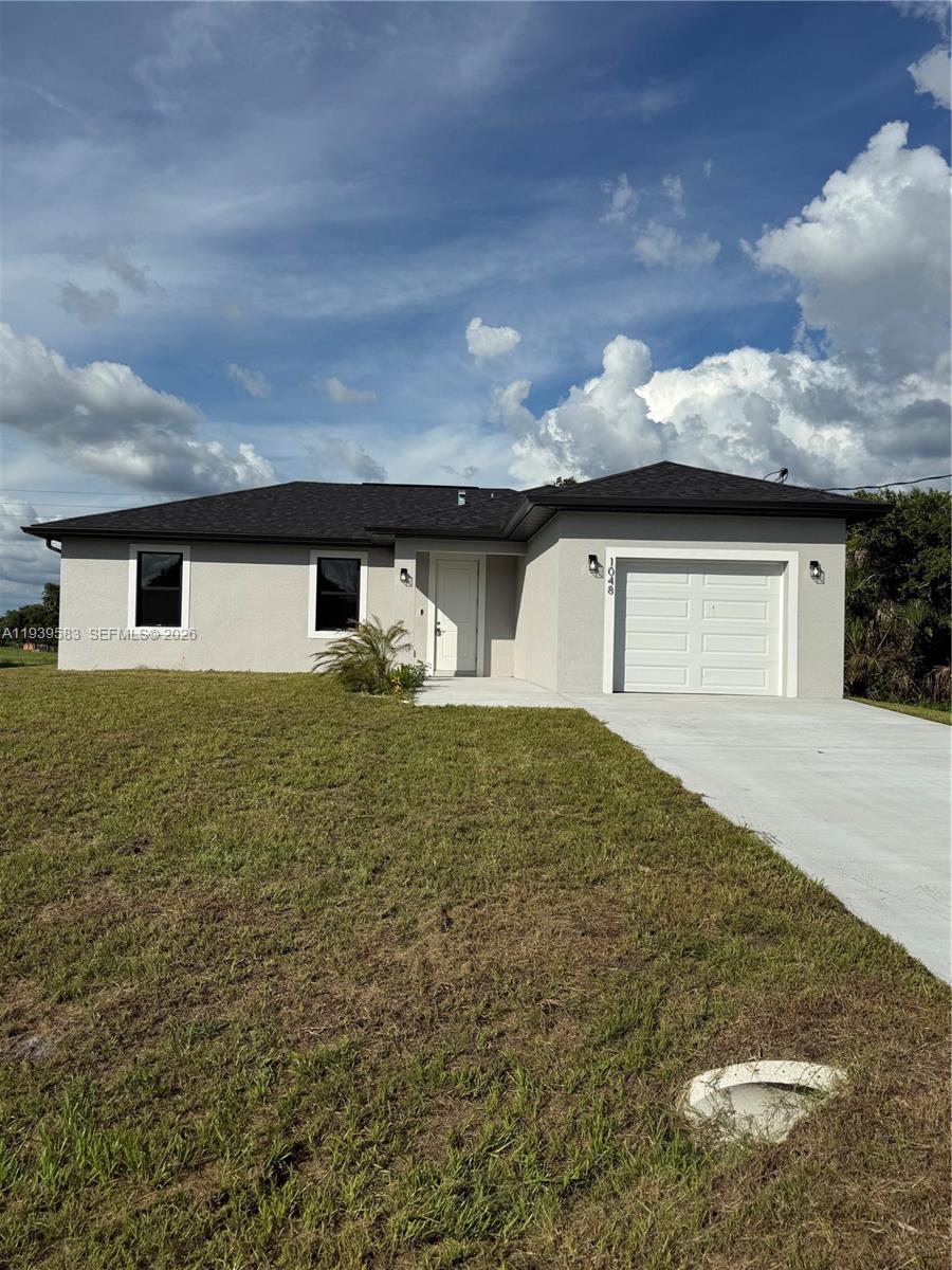 A single-story house with a gray stucco exterior, a dark roof, and a one-car garage — 1048 Jay Ct, La Belle FL 33935, LA BELLE, FL