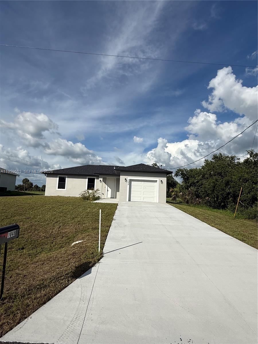 A single-story house with a light-colored exterior, a garage, and a concrete driveway — 1048 Jay Ct, La Belle FL 33935, LA BELLE, FL