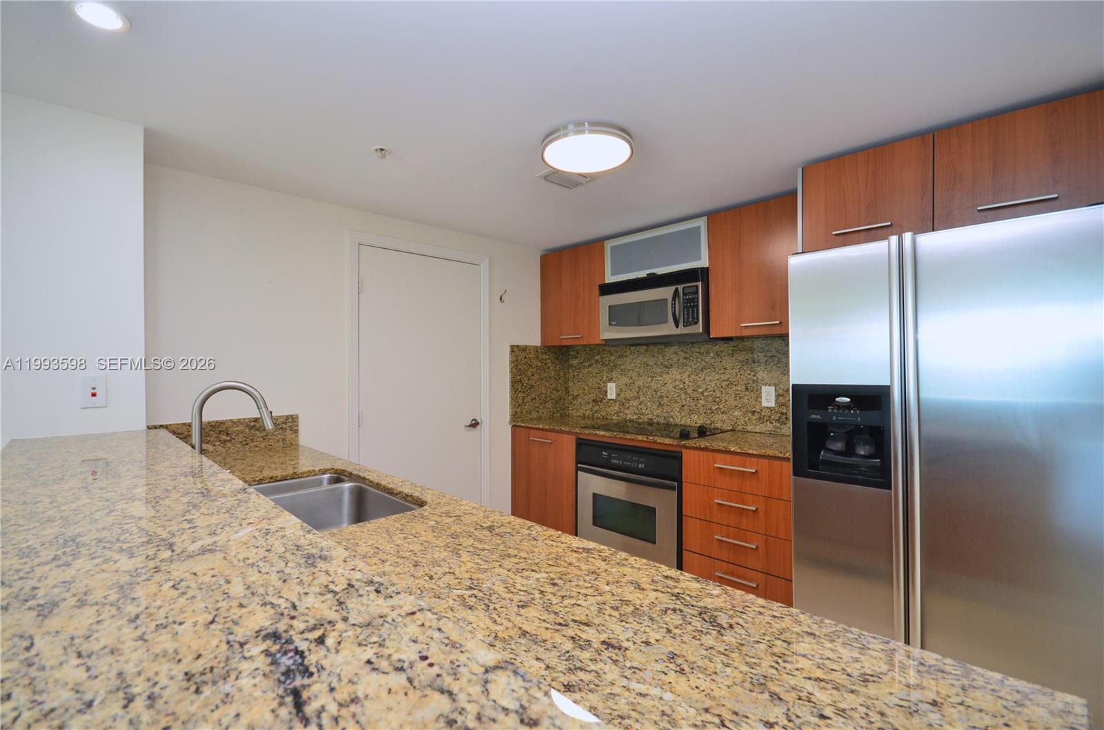 A dining area with a dark wood table and chairs sits beside an open kitchen — 9055 SW 73rd Ct # 1106, Miami FL 33156, MIAMI, FL