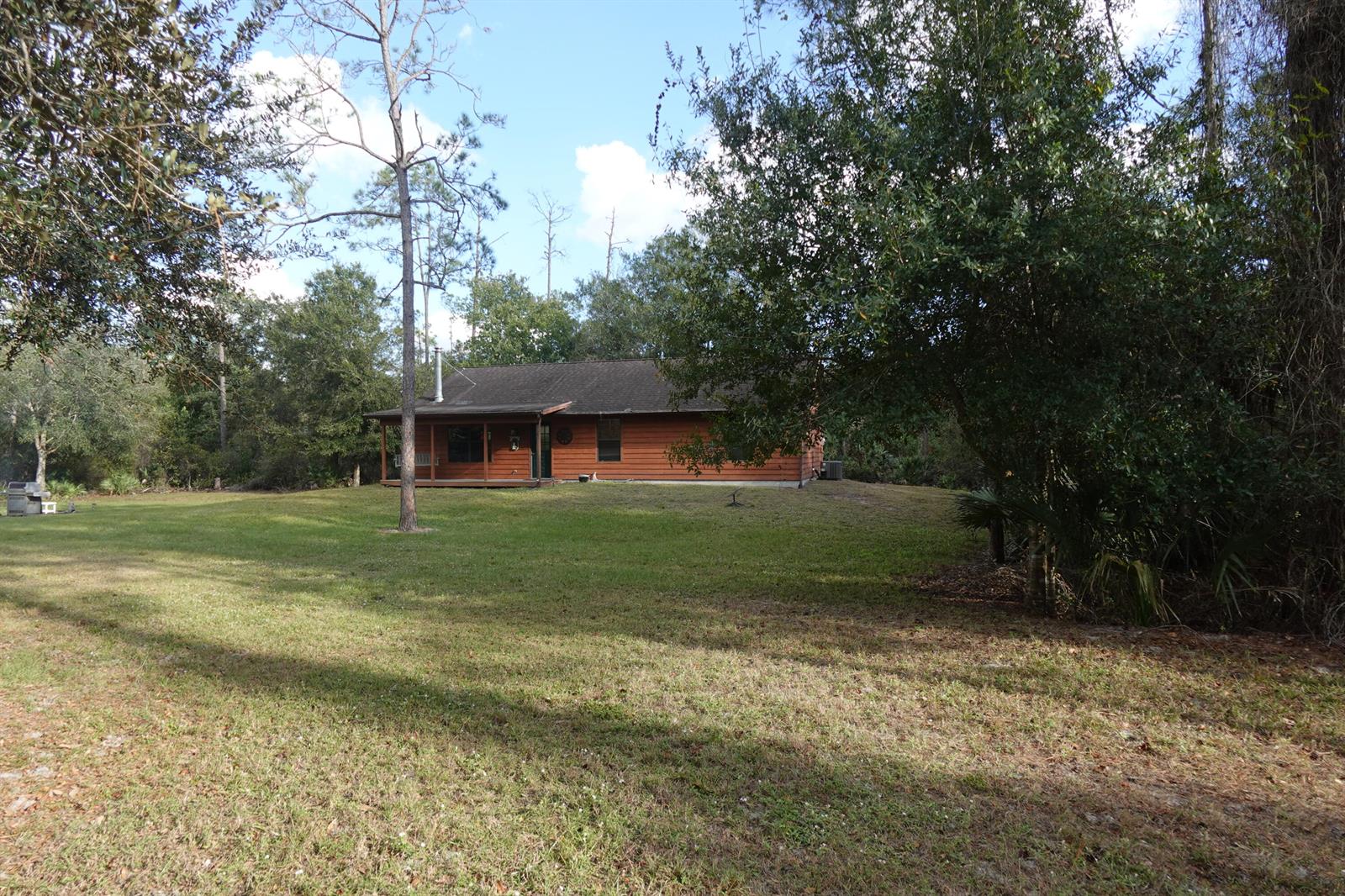 A wooden cabin with a front porch sits on a grassy lot surrounded by trees — 32801 N Us-441 Lot 187, Okeechobee FL 34972, OKEECHOBEE, FL