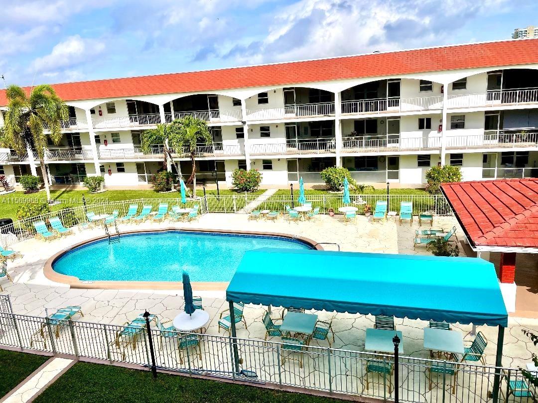 An outdoor swimming pool area with lounge chairs and a covered patio at an apartment complex — 580 Egret Dr # 308, Hallandale Beach FL 33009, HALLANDALE BEACH, FL