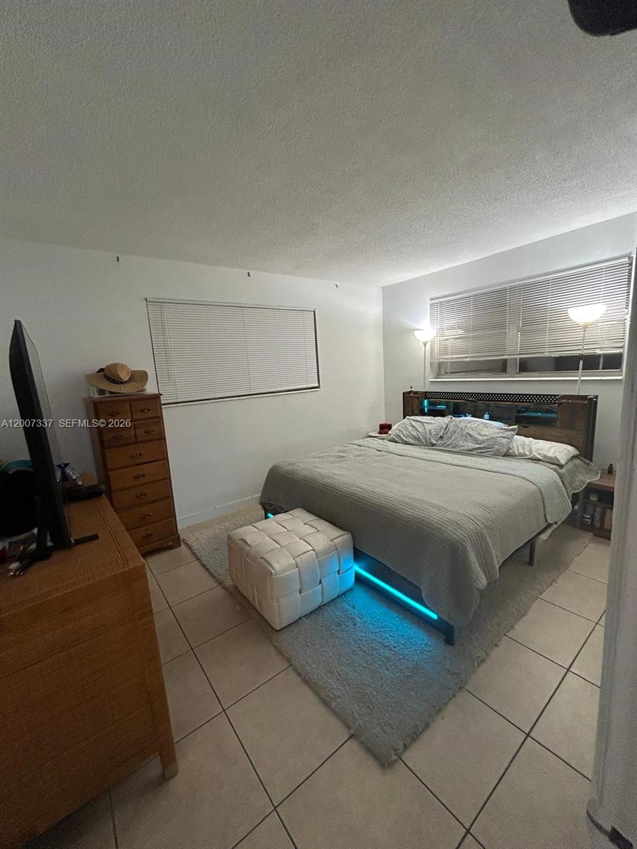 A bedroom features a bed with under-frame lighting, a dresser, and tiled flooring — 1100 NE 1st Ct # 104, Hallandale Beach FL 33009, HALLANDALE BEACH, FL