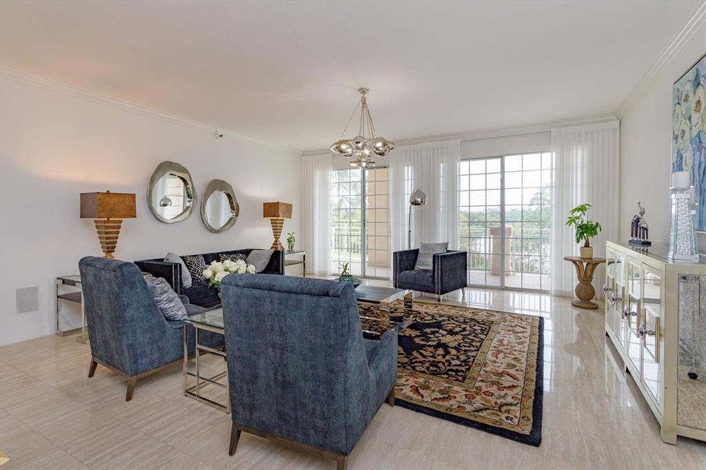 A bright living room features blue armchairs, a dark sofa, a patterned rug, and balcony access — 1110 W IVANHOE BOULEVARD UNIT 9, ORLANDO, FL