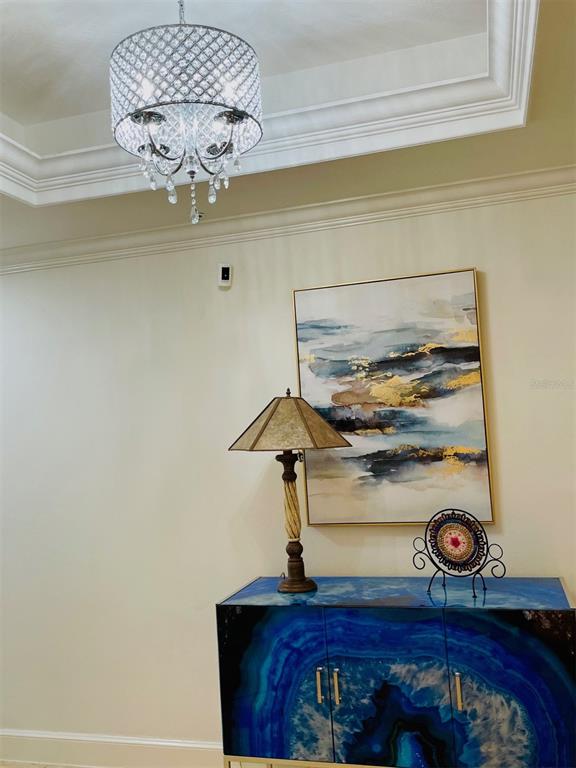 A room features a crystal drum chandelier, an abstract painting, a table lamp, and a blue cabinet — 1110 W IVANHOE BOULEVARD UNIT 9, ORLANDO, FL