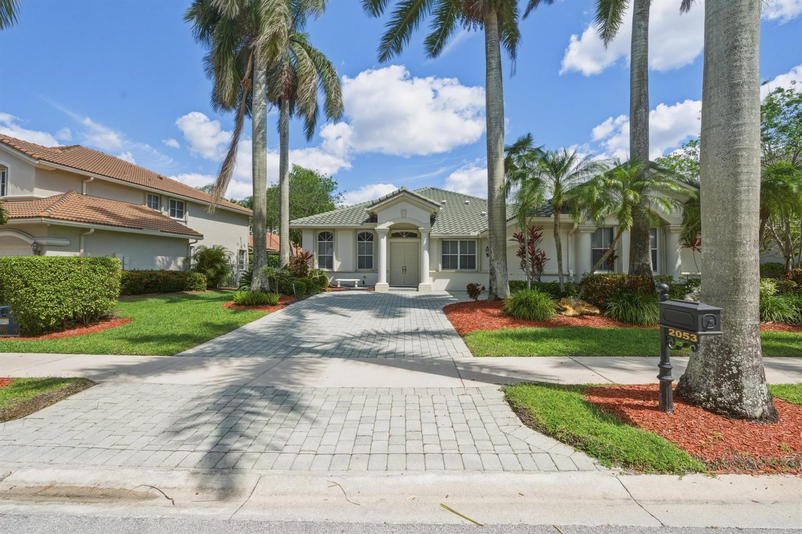 A single-story house with a paved driveway, palm trees, and a mailbox in the front — 2053 Quail Roost Drive, Weston FL 33327, WESTON, FL