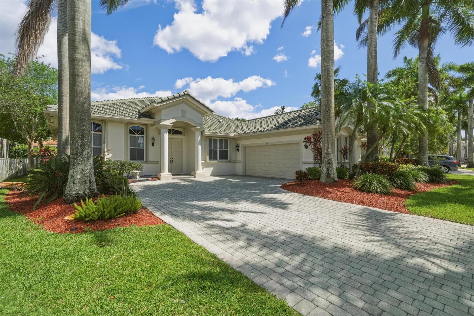 A single-story house with a paved driveway, palm trees, and a tiled roof — 2053 Quail Roost Drive, Weston FL 33327, WESTON, FL