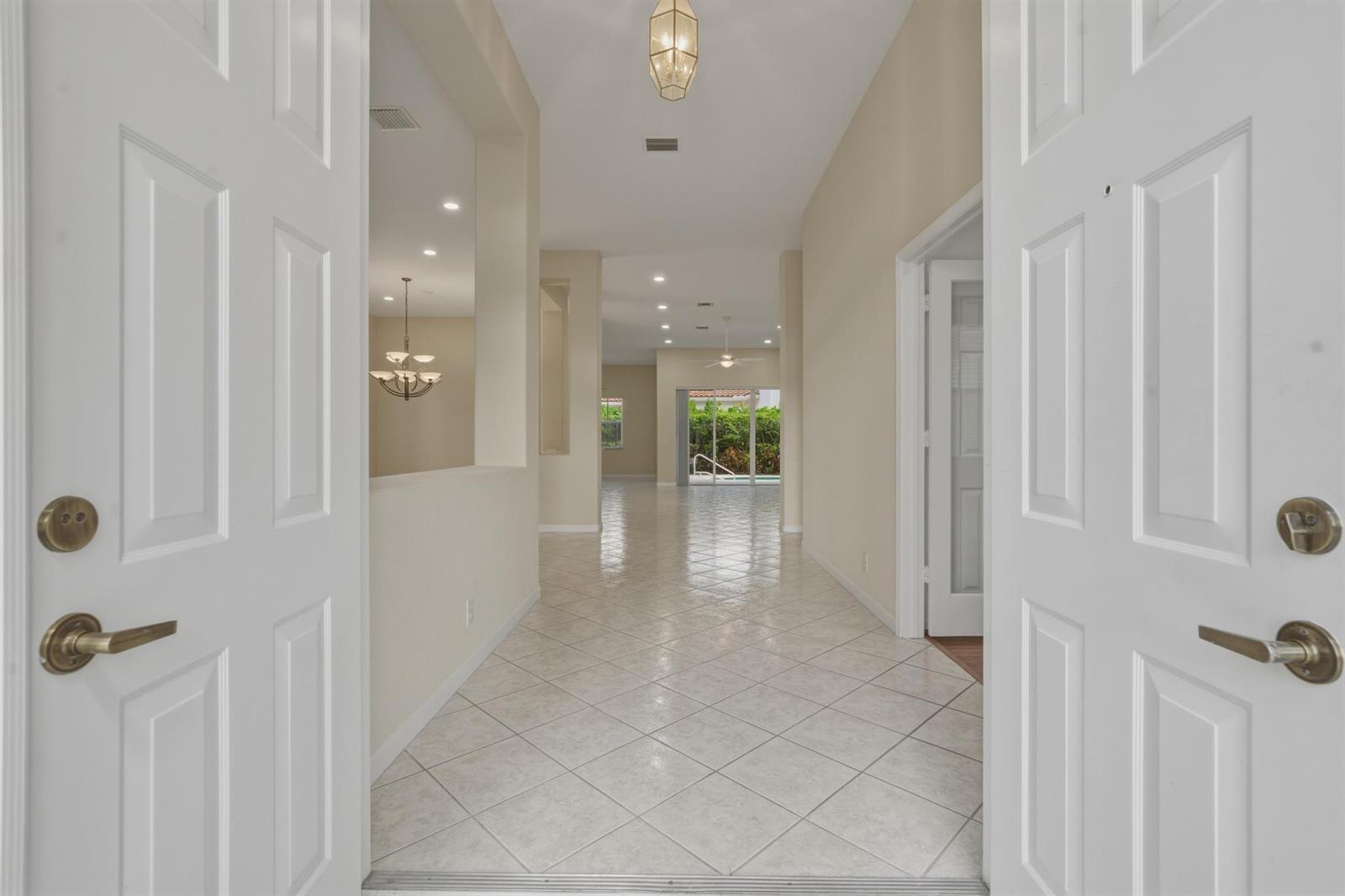 A tiled entryway leads into a bright, open-concept living area with a view of a pool — 2053 Quail Roost Drive, Weston FL 33327, WESTON, FL
