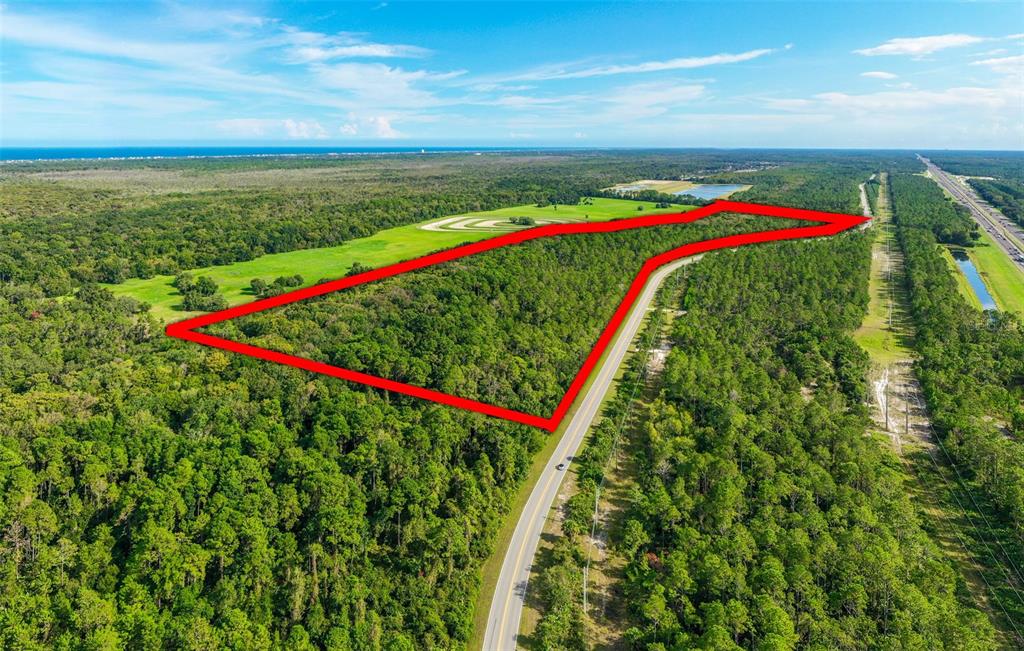 An aerial view shows a large, wooded plot of land outlined in red beside a road — xx OLD KINGS ROAD, PALM COAST, FL