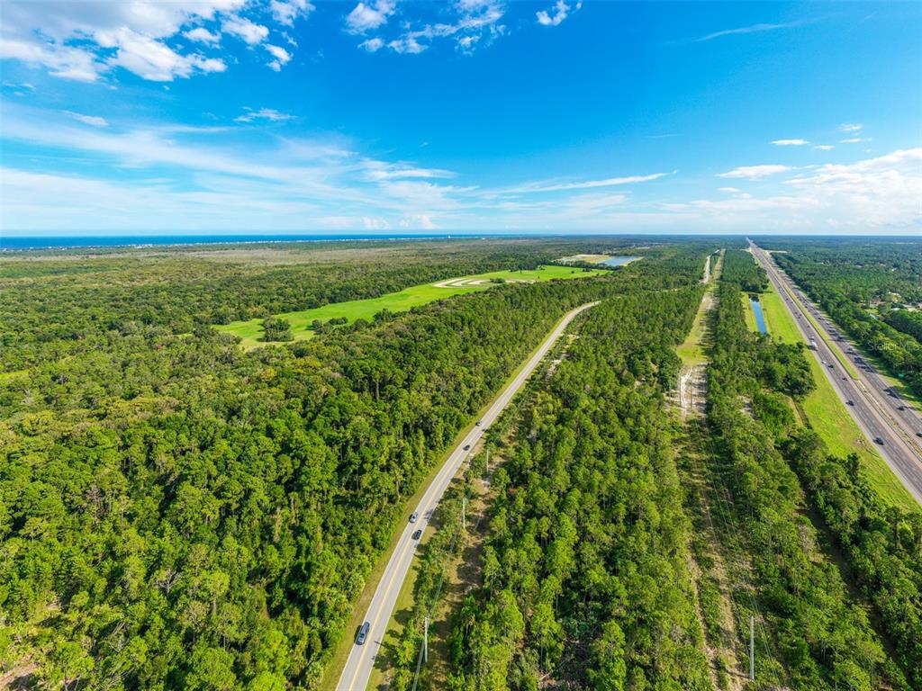 An aerial view shows a road running through a dense forest near a highway — xx OLD KINGS ROAD, PALM COAST, FL