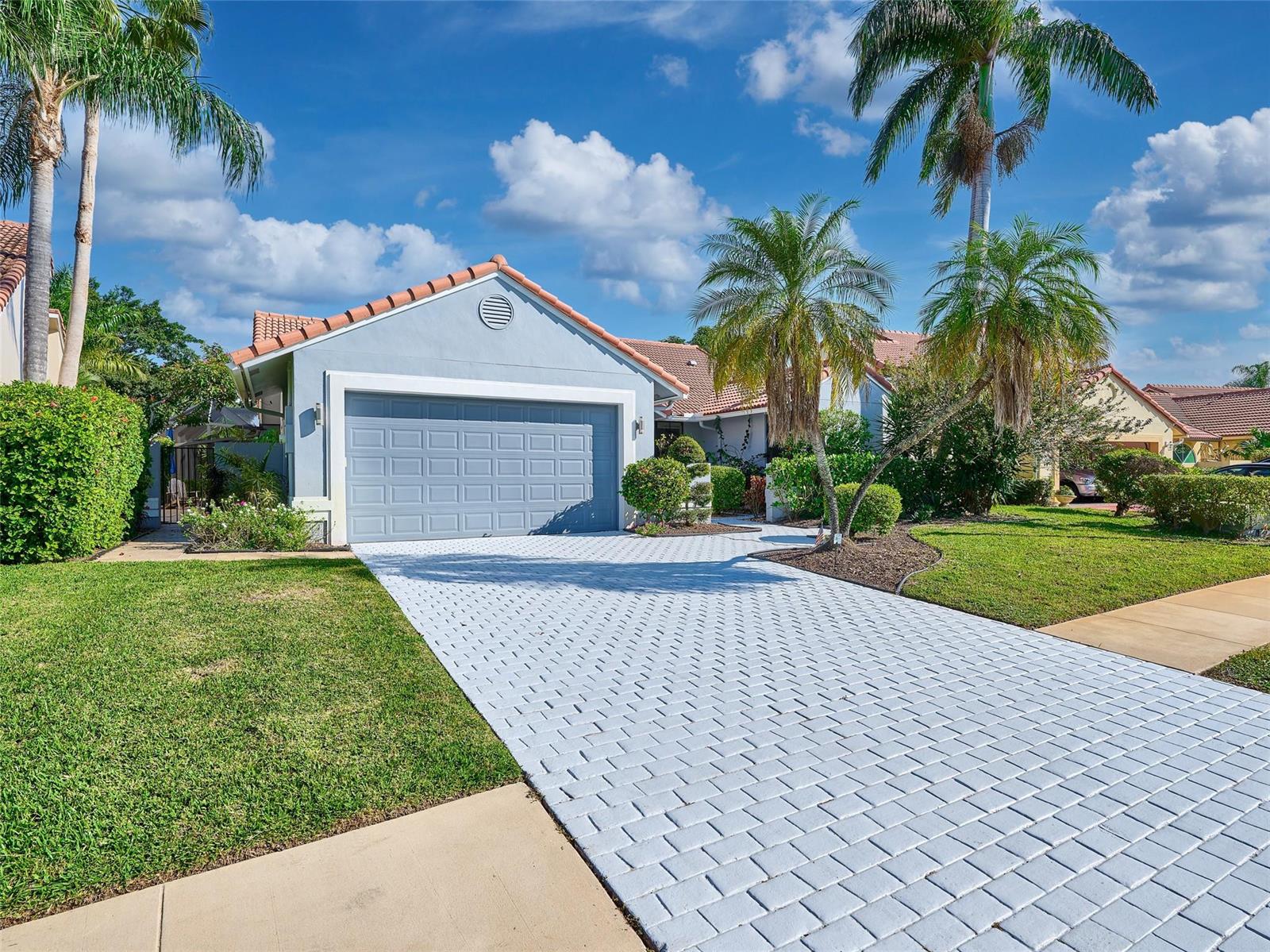 A light blue house with a tiled roof and a paved driveway under a blue sky — 19284 Cherry Hills Terrace, Boca Raton FL 33498, BOCA RATON, FL
