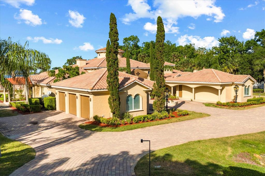A large Mediterranean-style house with a tile roof, three-car garage, and a paved circular driveway — 1112 ORANGE AVENUE, WINTER SPRINGS, FL