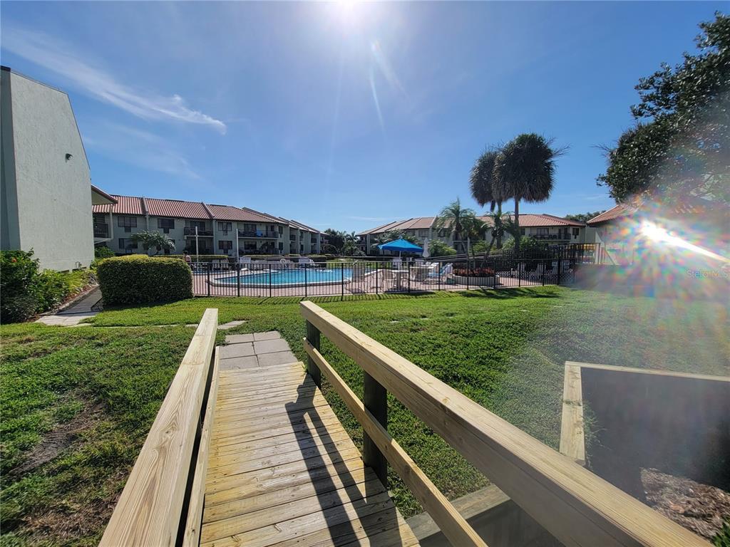 A swimming pool and circular hot tub are surrounded by a brick patio and lounge chairs — 1515 PINELLAS BAYWAY S UNIT 38, TIERRA VERDE, FL