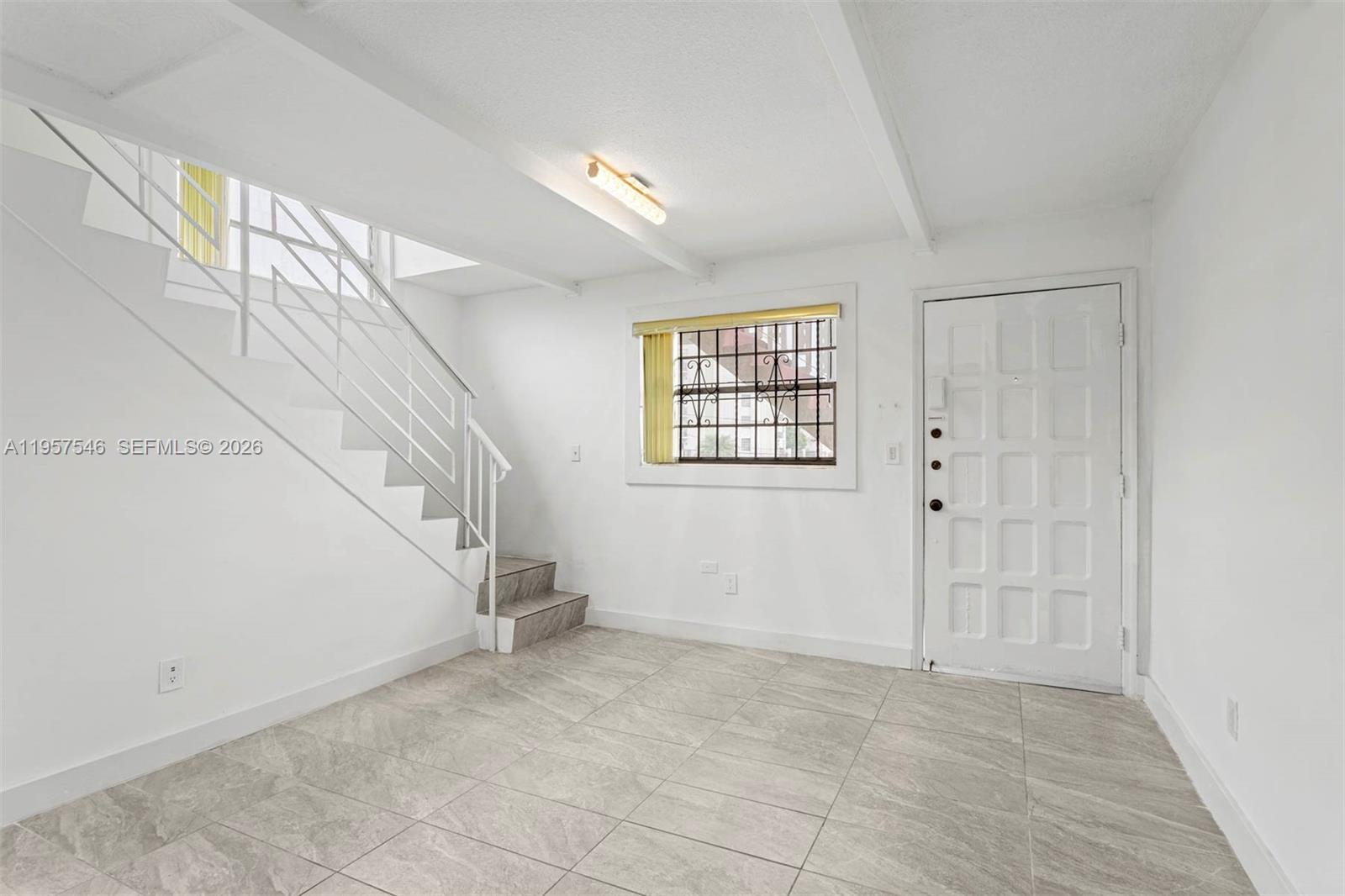 This room features white walls, tiled floors, a staircase with a railing, and a door — 1220 SW 5th St # 21, Miami FL 33135, MIAMI, FL
