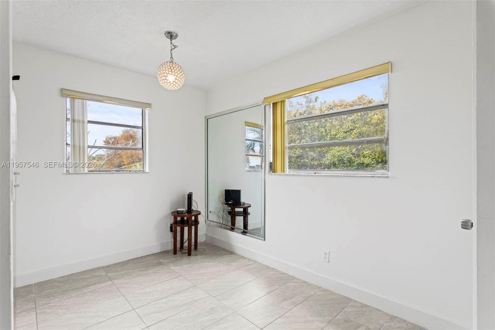 A room with white walls, tiled floors, two windows, and a large wall mirror — 1220 SW 5th St # 21, Miami FL 33135, MIAMI, FL