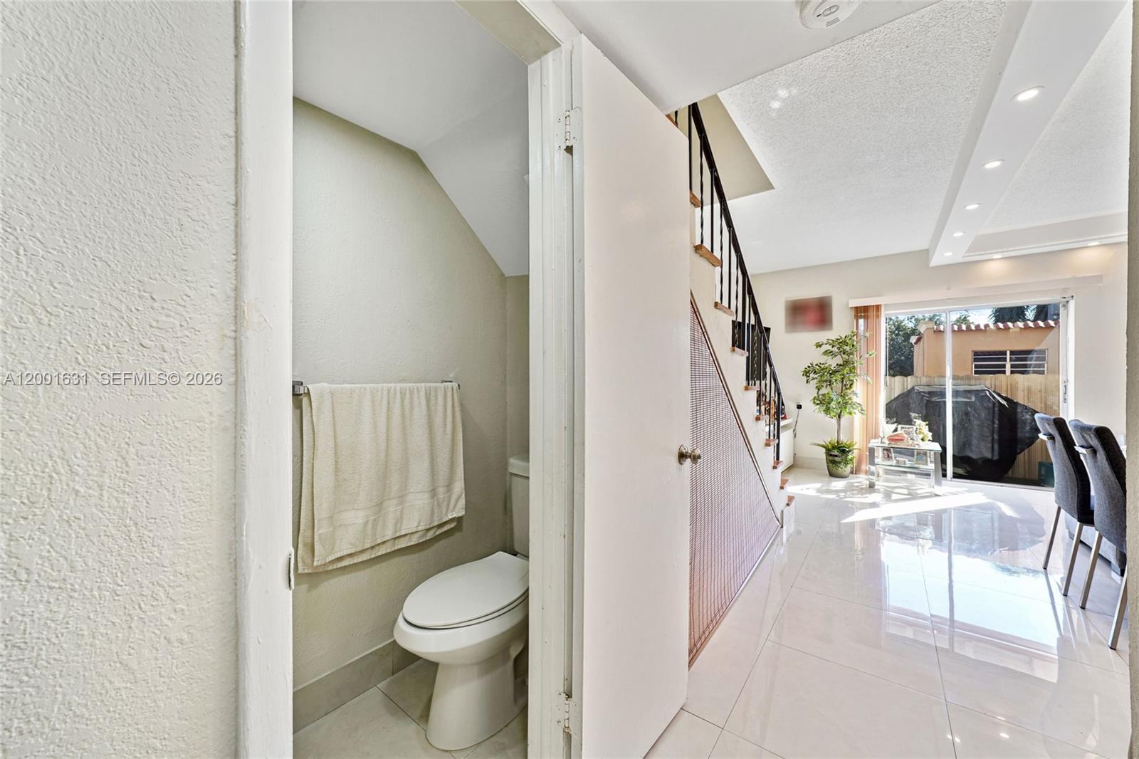 A small bathroom with a toilet is located next to a staircase and dining area — 1305 W 53rd St # 429, Hialeah FL 33012, HIALEAH, FL