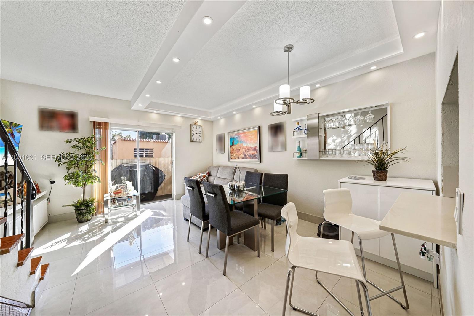 A dining area with a glass table, gray chairs, white bar stools, and tile flooring — 1305 W 53rd St # 429, Hialeah FL 33012, HIALEAH, FL