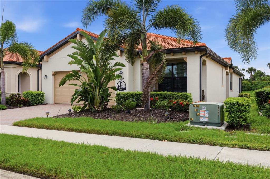 A single-story house with a tiled roof, garage, and palm trees in the front yard — 24173 SPARTINA DRIVE, VENICE, FL