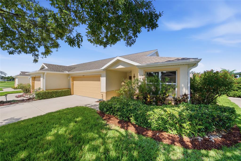 A single-story house with a tan garage, beige stucco exterior, and landscaped front yard — 3007 LIVE OAK LANE UNIT 34, PALMETTO, FL