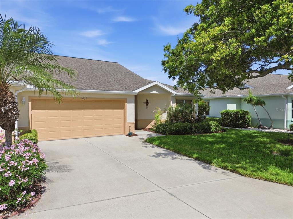 A single-story house with a tan garage, a concrete driveway, and a small front yard — 3007 LIVE OAK LANE UNIT 34, PALMETTO, FL