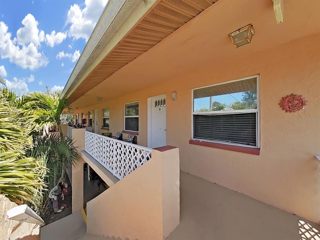 An exterior view of a second-story apartment balcony with a white door and railing — 206 22ND AVENUE, INDIAN ROCKS BEACH, FL