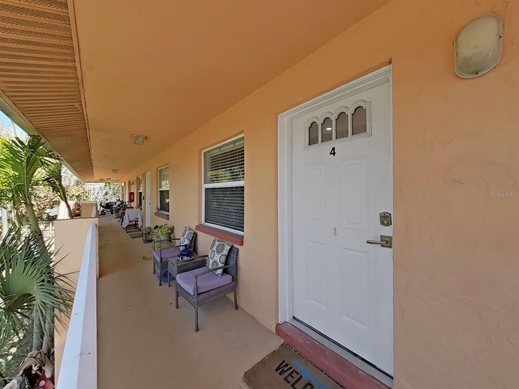An exterior walkway with a white door labeled number four and outdoor seating — 206 22ND AVENUE, INDIAN ROCKS BEACH, FL