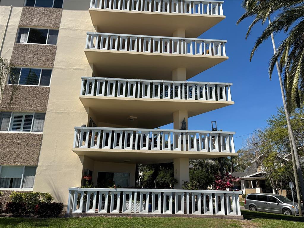 A multi-story apartment building features stacked balconies with white decorative railings and beige exterior walls — 1200 N SHORE DRIVE NE UNIT 212, ST PETERSBURG, FL