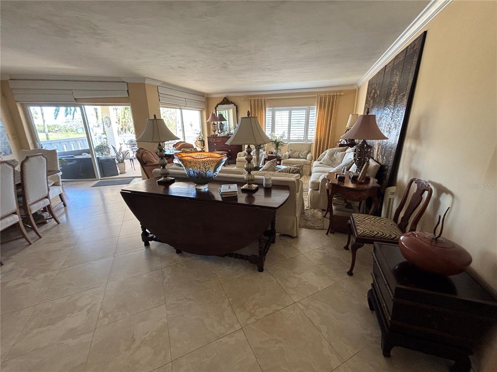 A spacious living room features tile flooring, a large sofa, and a dark wood console table — 1200 N SHORE DRIVE NE UNIT 212, ST PETERSBURG, FL