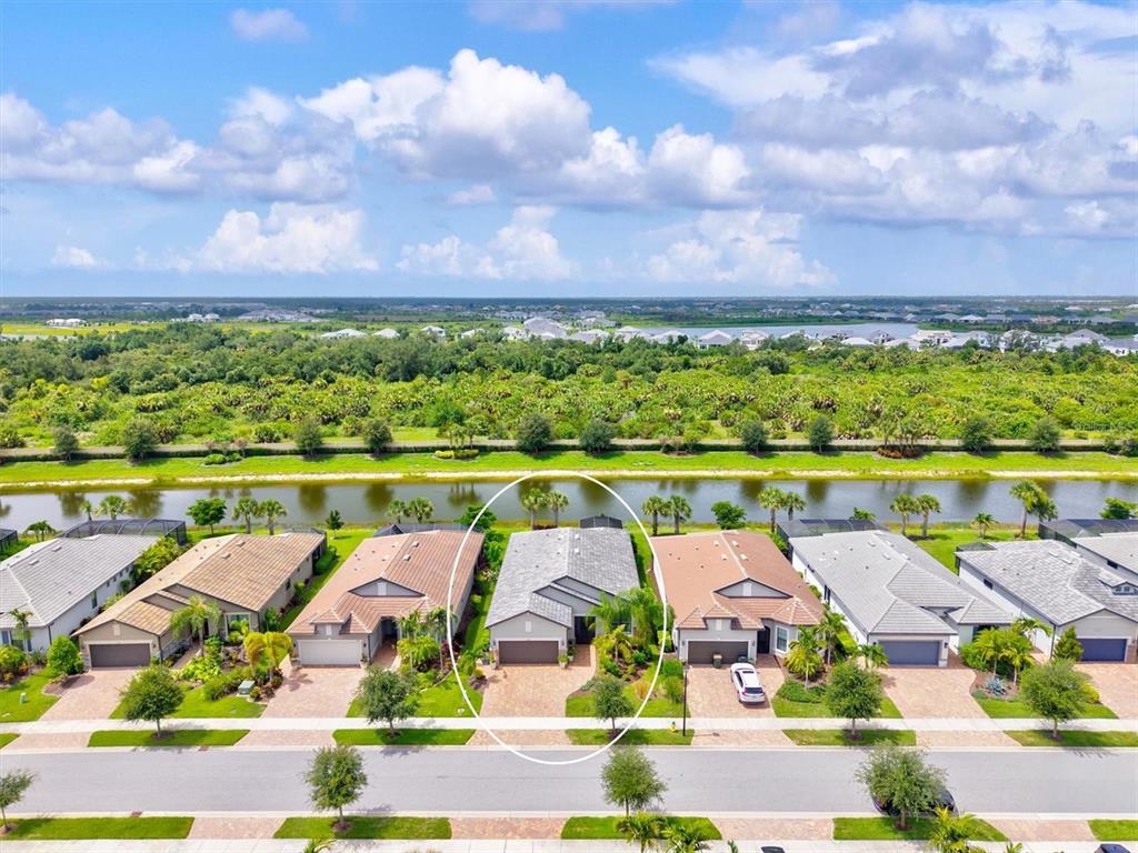 An aerial view shows a row of suburban houses situated along a canal and greenery — 13179 BORREGO STREET, VENICE, FL