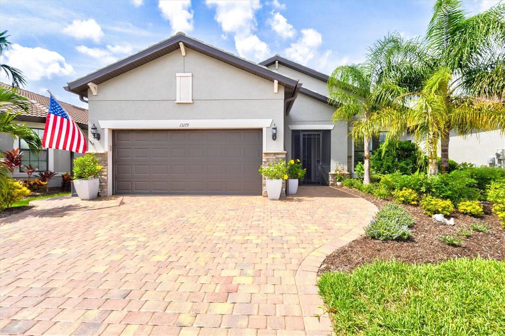 A paved walkway leads to the front entrance of a house with stone accents — 13179 BORREGO STREET, VENICE, FL