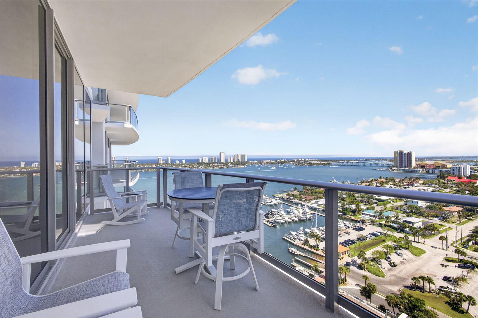 A high-rise balcony features outdoor furniture overlooking a marina, a bridge, and the ocean — 220 Lake Shore Drive # 1907, West Palm Beach FL 33403, WEST PALM BEACH, FL