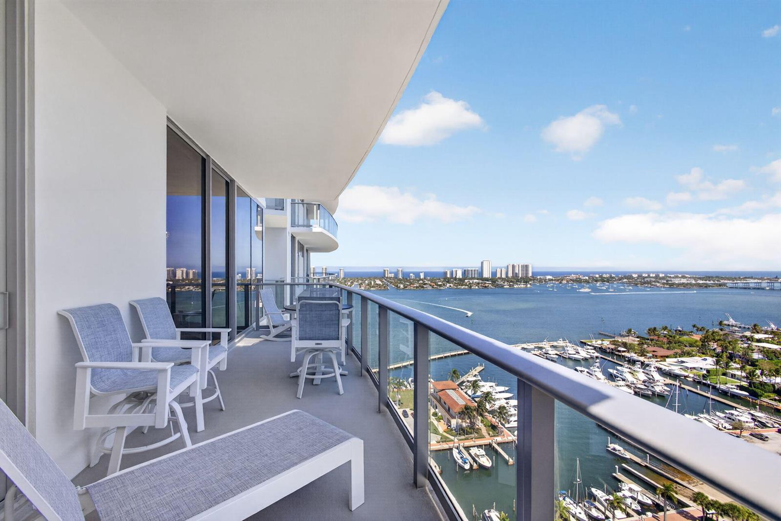 A high-rise balcony features outdoor furniture overlooking a marina and a coastal city skyline — 220 Lake Shore Drive # 1907, West Palm Beach FL 33403, WEST PALM BEACH, FL