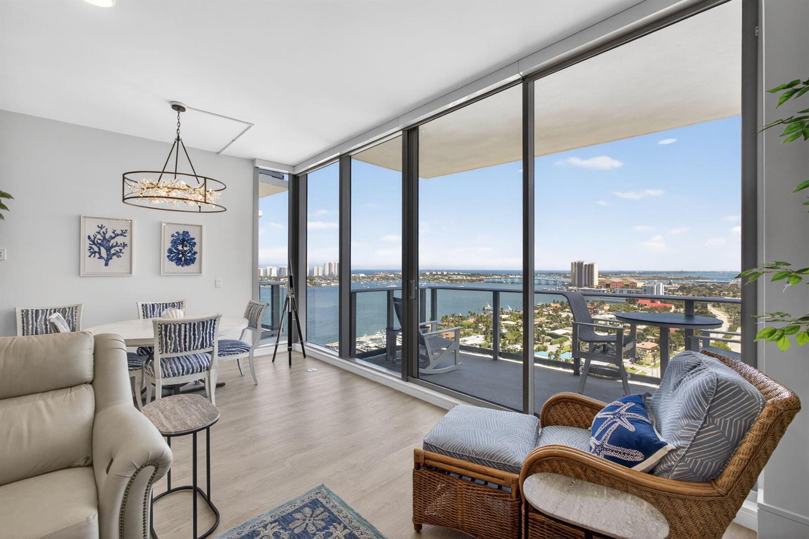 A living and dining area features floor-to-ceiling windows with a balcony overlooking the water — 220 Lake Shore Drive # 1907, West Palm Beach FL 33403, WEST PALM BEACH, FL