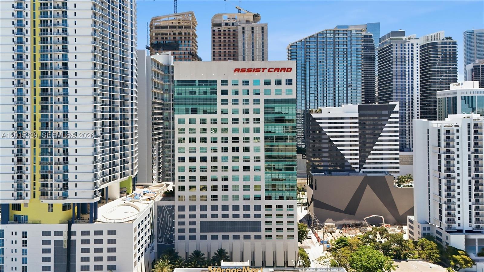 An aerial view shows a tall, white office building with the Assist Card logo — 175 SW 7th St # 1614, Miami FL 33130, MIAMI, FL