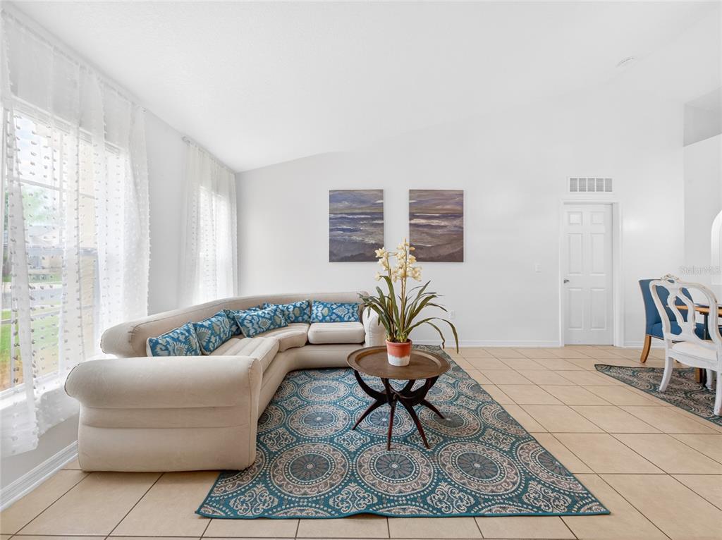 A living room features a beige sectional sofa, a patterned area rug, and tile flooring — 2589 HUNLEY LOOP, KISSIMMEE, FL