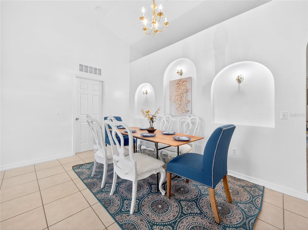 A dining room features a wooden table, blue and white chairs, and three arched wall niches — 2589 HUNLEY LOOP, KISSIMMEE, FL
