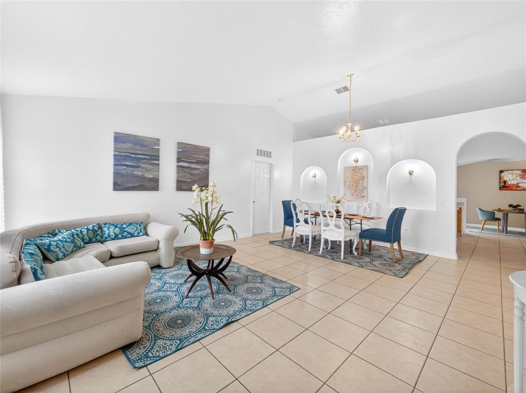 A living and dining area features white walls, tile flooring, and arched wall niches — 2589 HUNLEY LOOP, KISSIMMEE, FL